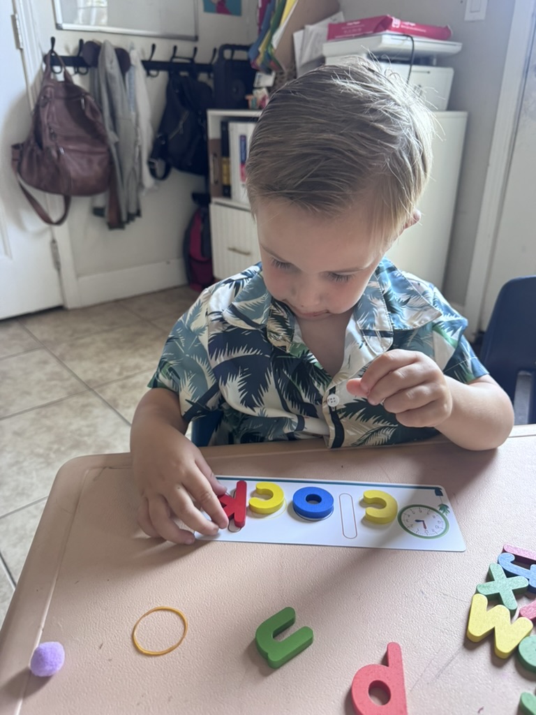Preschooler spelling a word with colorful letter tiles at a learning table