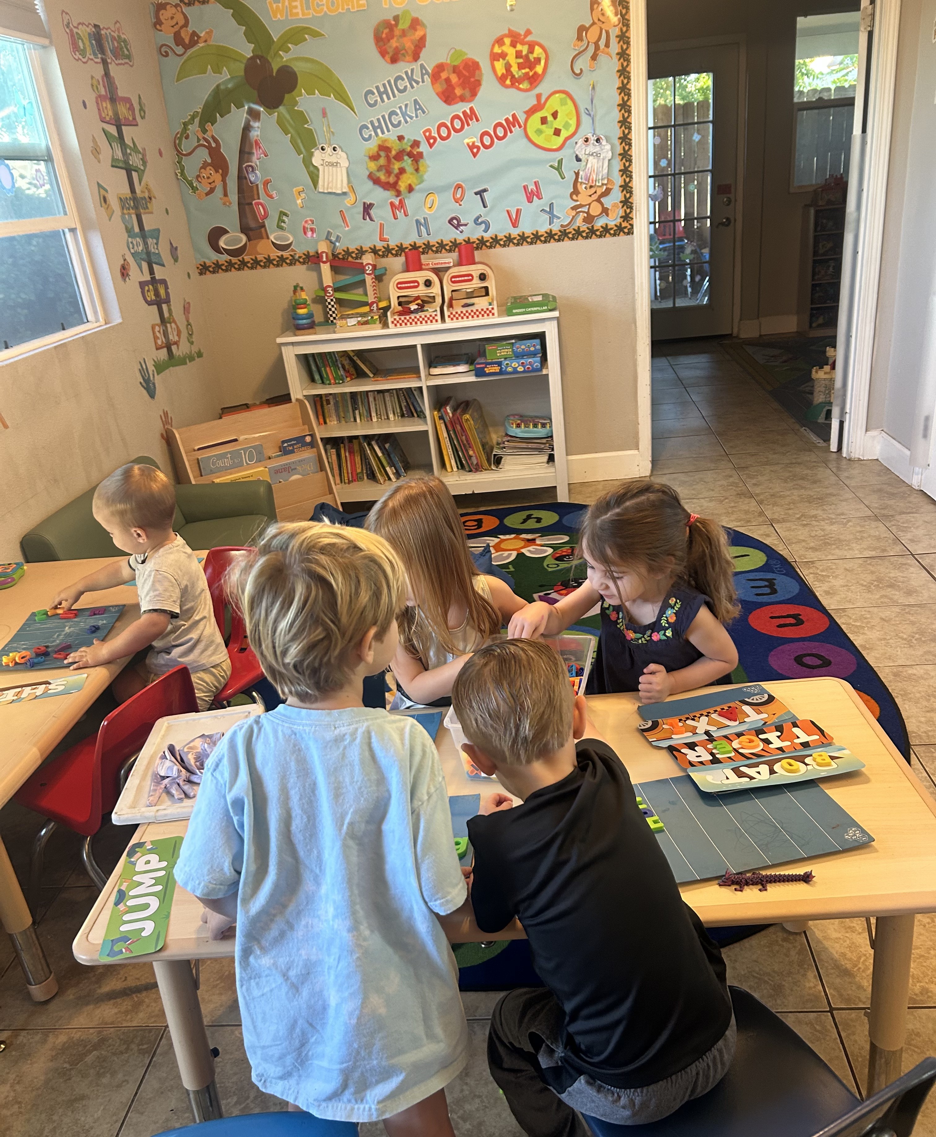 Preschool children playing with letter puzzles at a classroom table