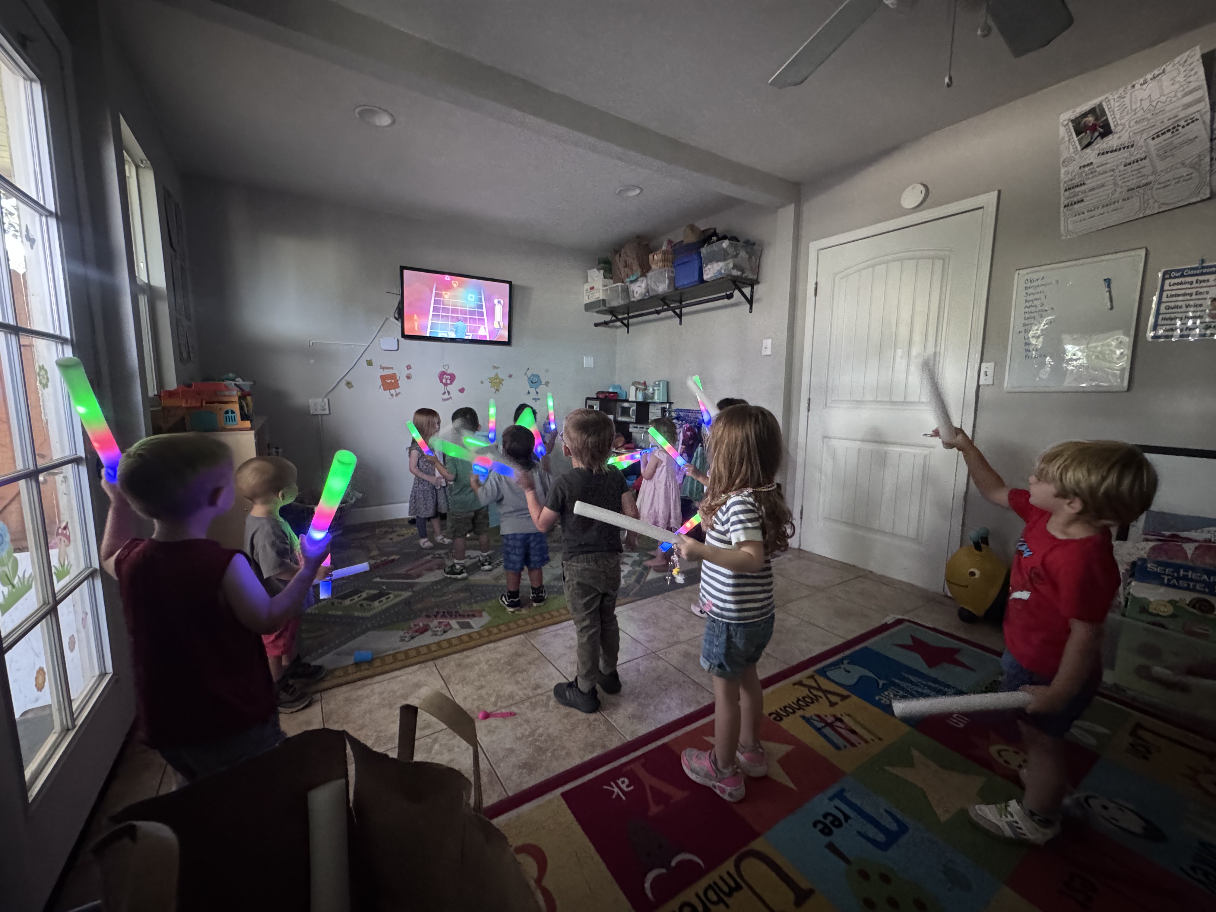 Preschoolers dancing with glowing light-up batons during music time in the classroom