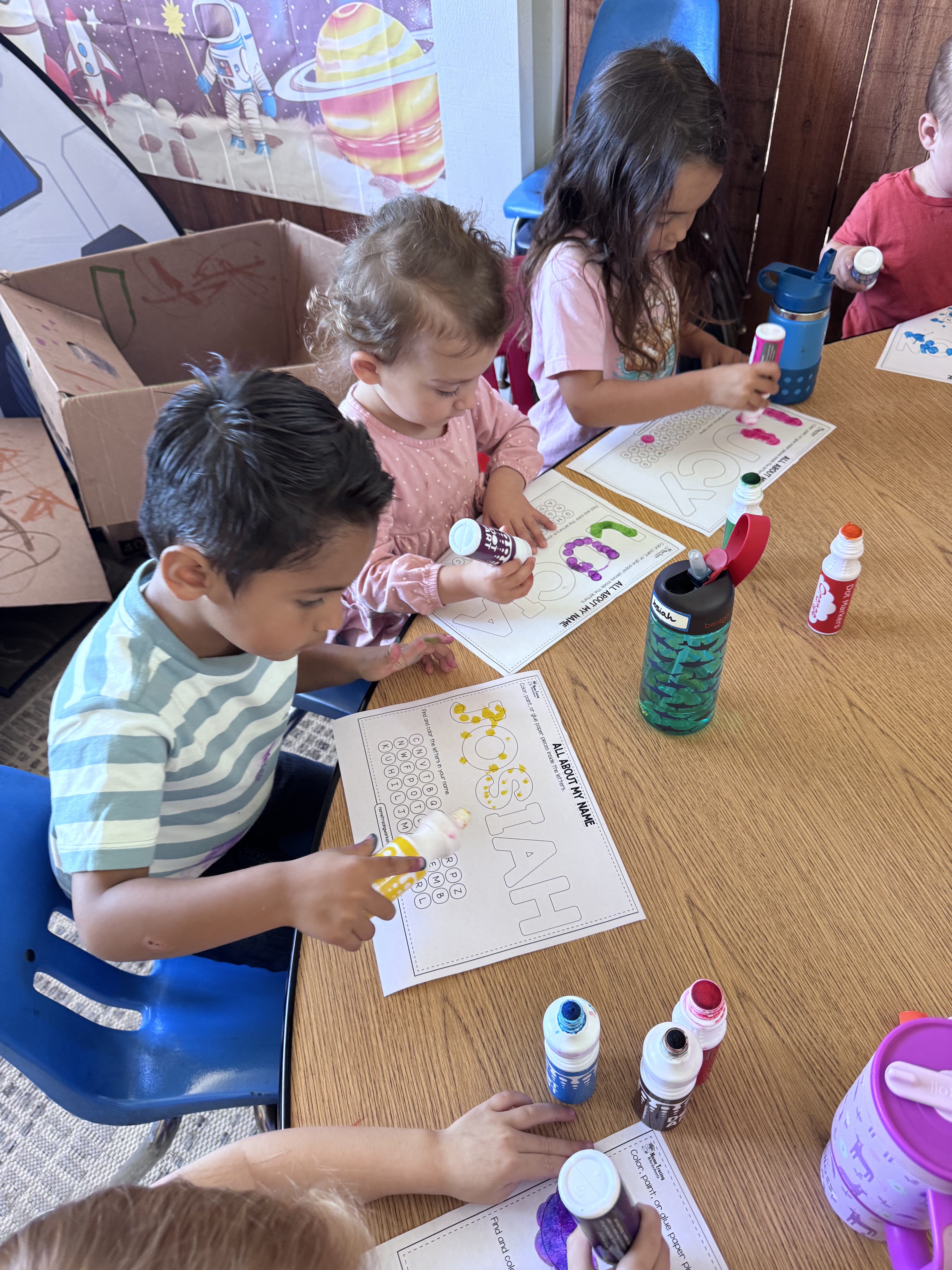 Preschoolers painting the letters of their names with dot markers